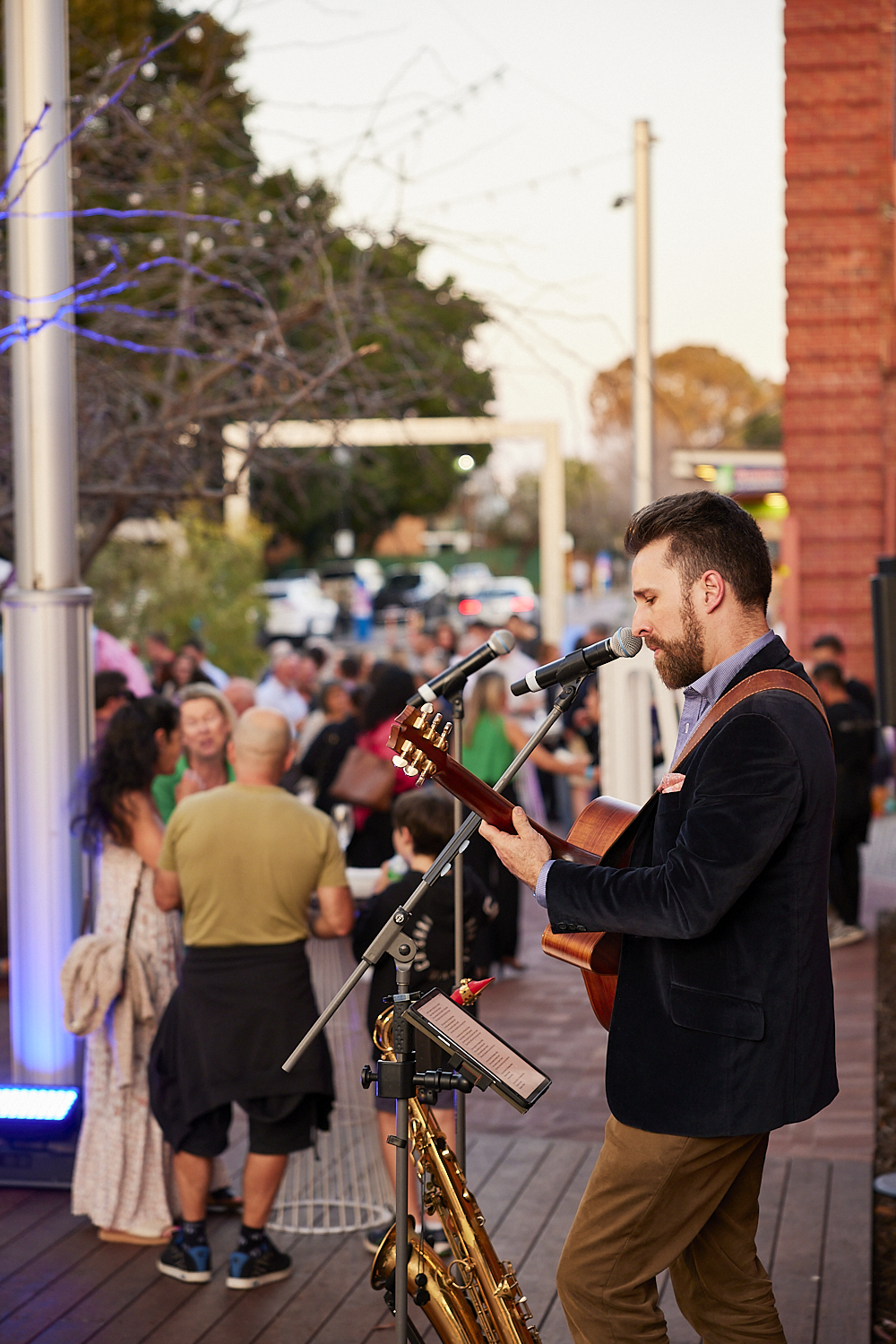 A musical entertainer plays music for a crowd in a newly upgraded public space.