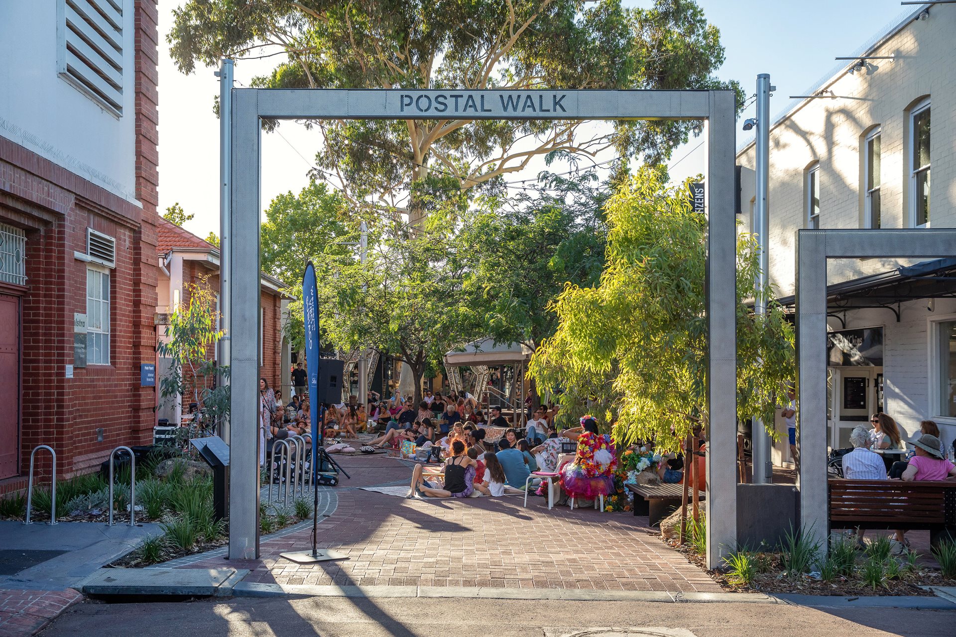 People sitting on the newly upgraded decking, picnic style, listening to live entertainment.