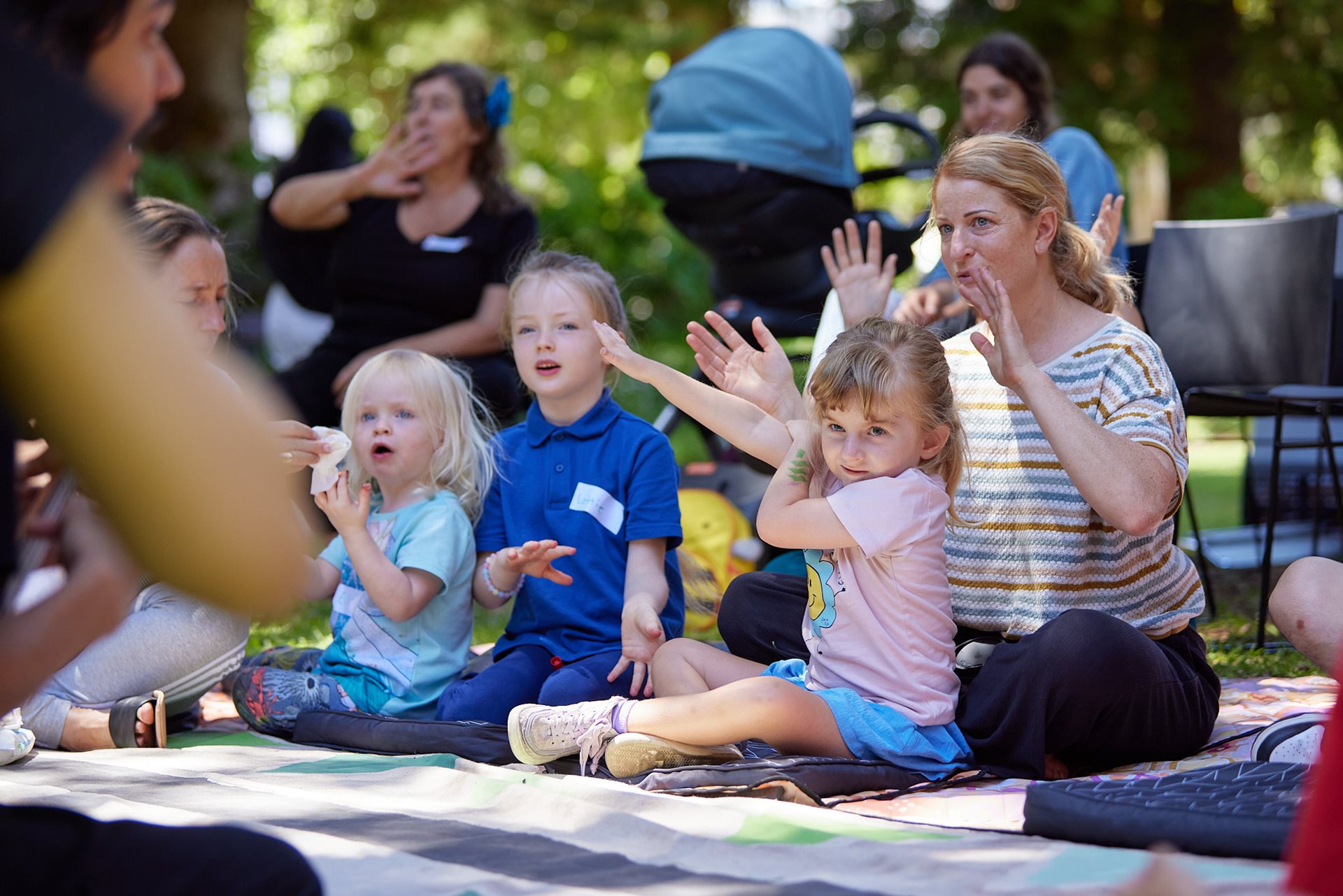 Children playing and clapping to nursery rhymes in garden